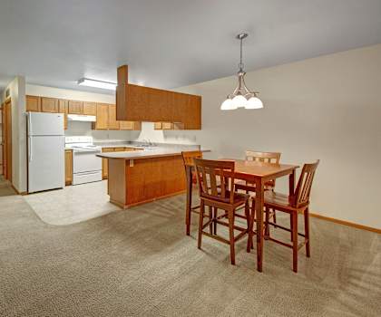 The dining room with a dining table and chairs and a view of the kitchen at Dakota Apartments. 