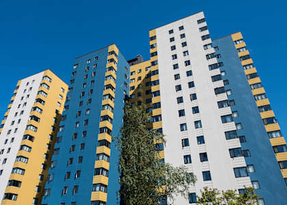 A tall building with a blue and yellow facade stands against a clear sky.