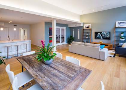 A modern living room with a wooden table and white chairs.