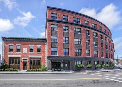 A red brick building with a black awning on the corner.
