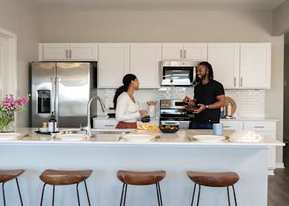 a man and woman standing in a kitchen preparing food at Rialto Townhomes Apartments, Waukee, Iowa