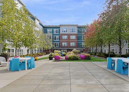 A courtyard with tables and chairs and a building in the background.