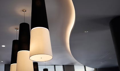 A series of modern, curved, white and black lampshades hang from the ceiling.