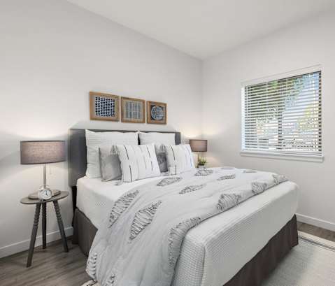 A bedroom with a large bed and a window with blinds.