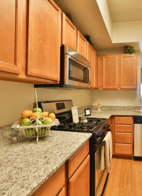 a kitchen with wood cabinets and granite counter tops and stainless steel appliances at Mariposa at Elk Drive, Burleson