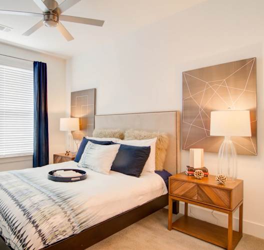 A bedroom with a bed, nightstand, and a ceiling fan.