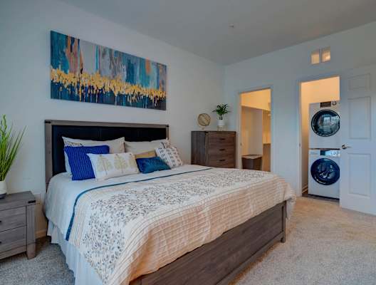 A bedroom with a large bed and a painting on the wall.