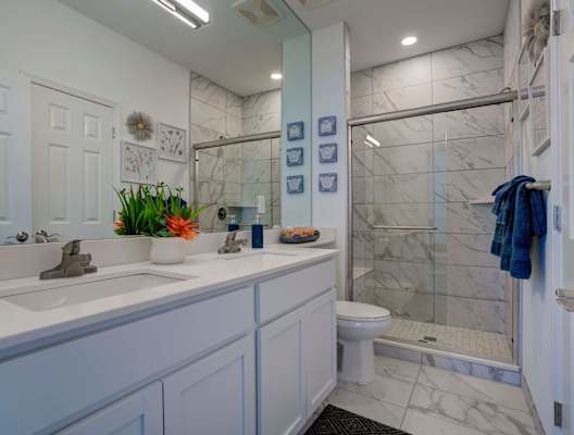A white bathroom with a sink, toilet, and shower.