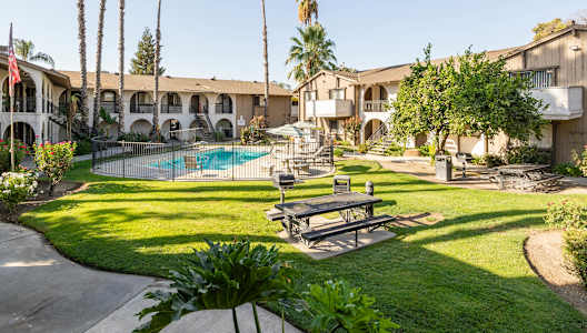 A pool surrounded by a fence and a bench in the foreground.
