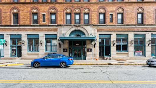 A blue car is parked in front of a building with a green awning at Mohican Apartments, New London, CT, 06320