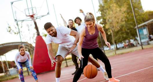 A group of people playing basketball on an outdoor court.