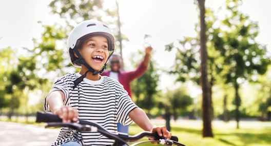 A child in a striped shirt is riding a bicycle in a park.