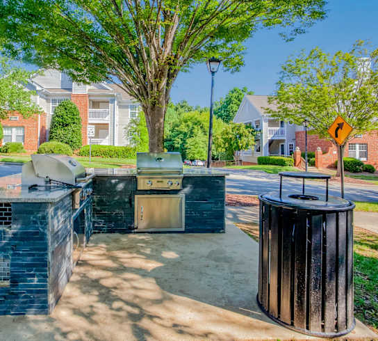 A blue dumpster sits in the foreground of a residential street.