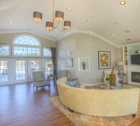A living room with a yellow couch and a fireplace.