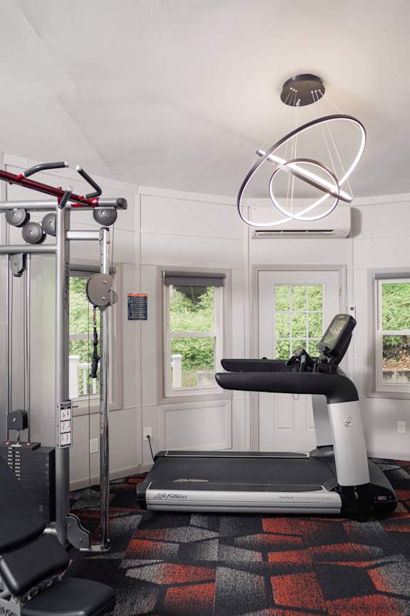 a gym with a treadmill and weights and a tv at Woodbury, Woodbury, CT, 06798
