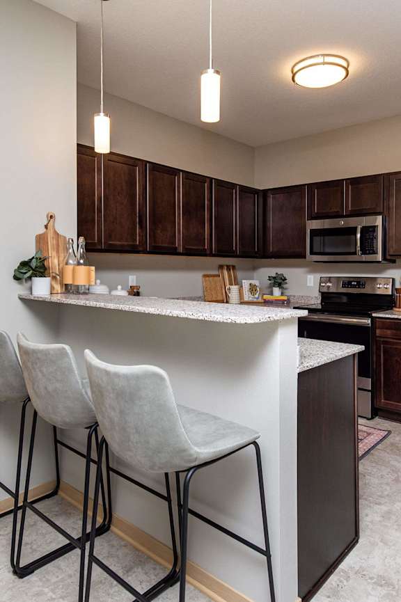 spacious kitchen with stainless steel appliances and a bar with three stools at Lake Shore Apartments, Ankeny