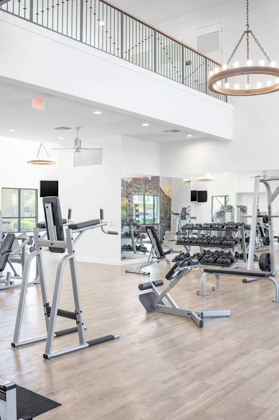 A spacious gym with a variety of equipment and a balcony overlooking the workout area.