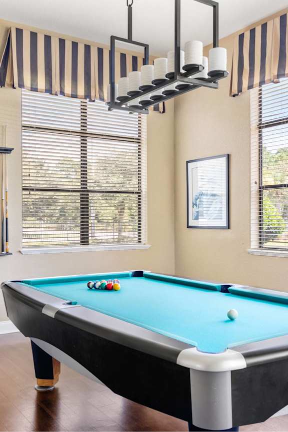 A pool table in a room with a window and a cabinet.