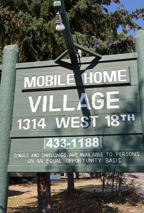 a sign for mobile home village in front of a tree at Mobile Home Village, Cheyenne, Wyoming