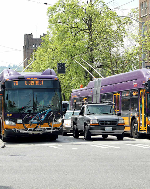 two buses and a car on a city street