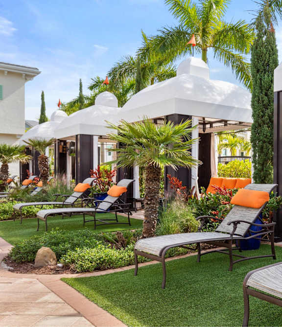 A white gazebo is surrounded by lawn chairs and plants.