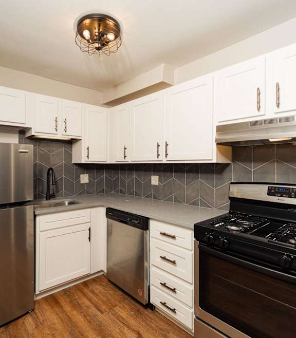 a modern kitchen with stainless steel appliances and white cabinets at Retro 511 Apartments, Connecticut