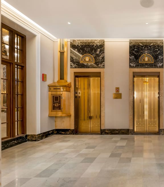 the lobby of a building with four gold doors and a marble floor at the Belden Stratford in Chicago, IL