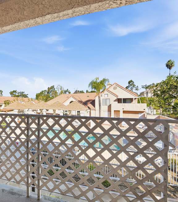 A balcony with a lattice railing overlooks a residential area. at Whispering Fountains Diamond Bar, California
