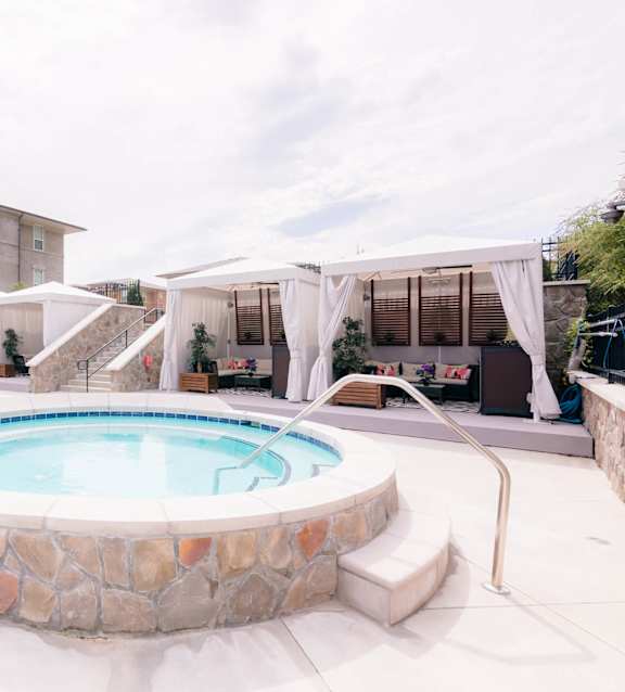 a pool with chairs and umbrellas next to a pool at The Villa at River Pointe, Maumelle, AR 72213