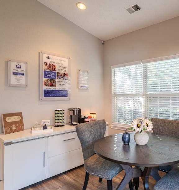 A dining room with a table set for two and a window with blinds.at The Village at England Run, Fredericksburg