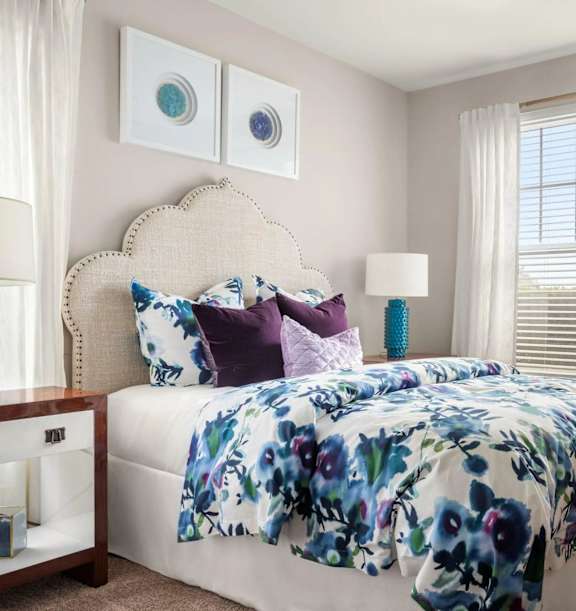 A bedroom with a floral bedspread and a white bed.