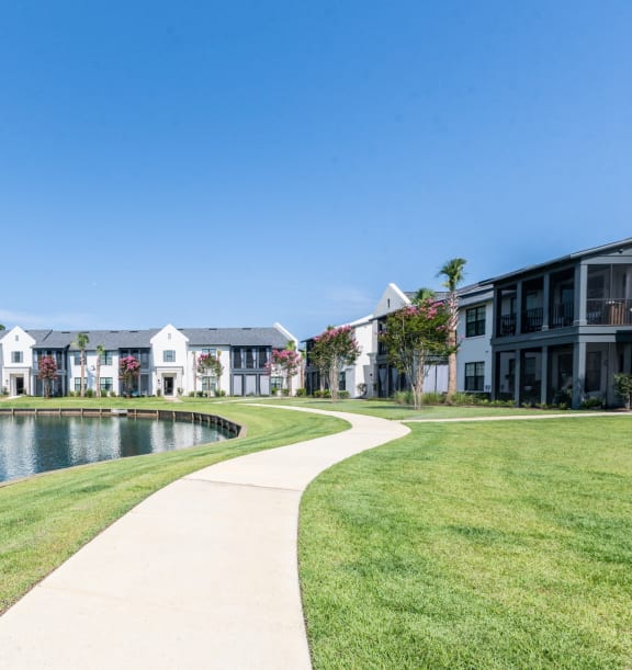 a sidewalk next to a lake with apartments in the background at 393 North Apartments, Santa Rosa Beach, Florida