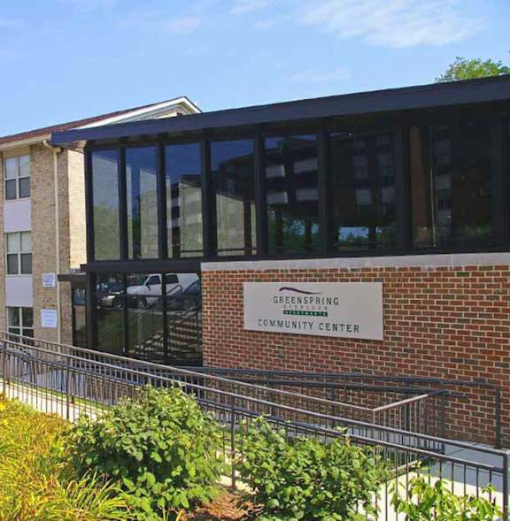 A red brick apartment building with a green lawn in front.