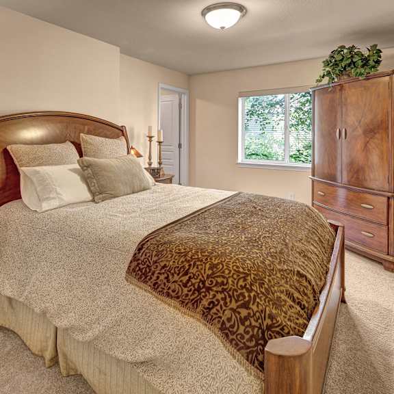 A bedroom with a bed and a dresser and a window at Admirals Cove Apartments.