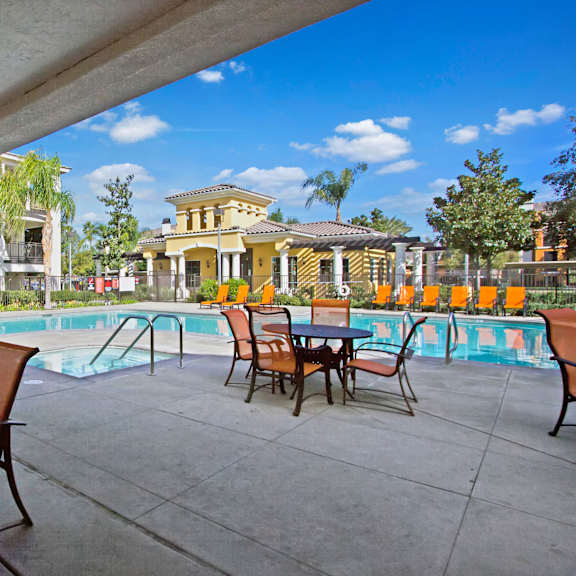 Patio area by the pool with tables and chairs at Fresco Apartments. 
