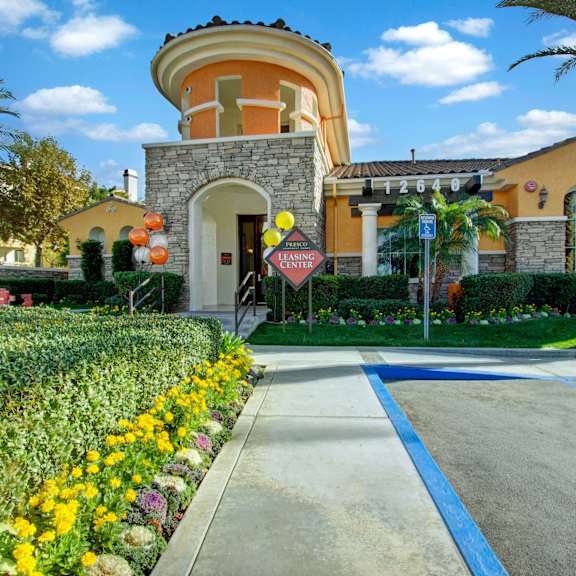 A sidewalk in front of the entrance to the Fresco leasing center with flowers and plants. 