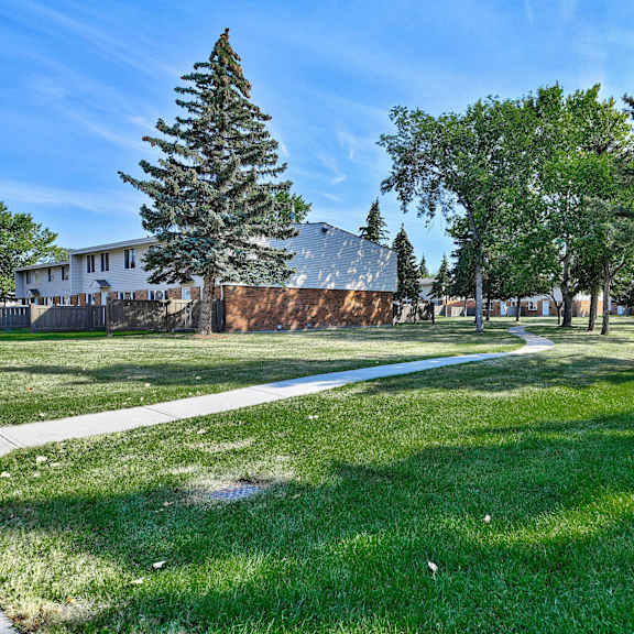 Trees, grassy area, and paths outside of Ranchlands Apartment Homes. 