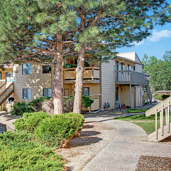 The exterior of the apartments and the green space with grass, trees, and shrubs at Grand View. 