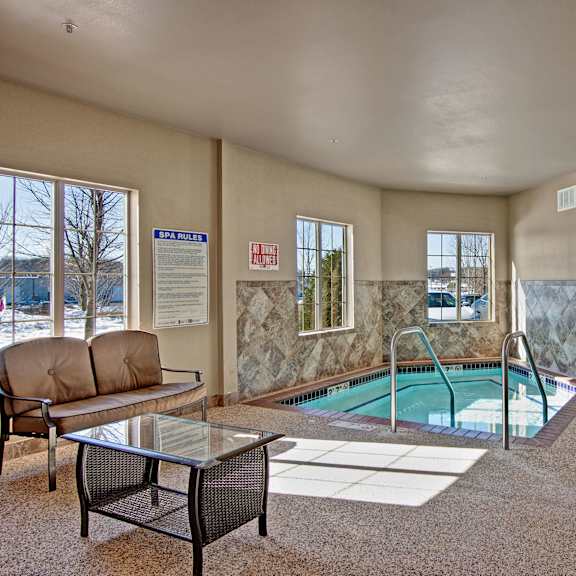 The turquoise indoor jacuzzi surrounded by seating and a plant at Grand River Estates. 