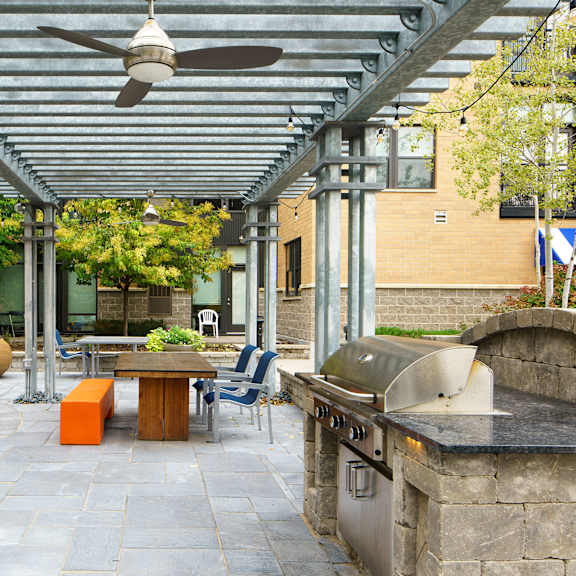 An outdoor patio with a table, chairs, fan, fireplace, and grill at Marbella on Dean.