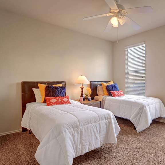 A bedroom with two twin beds and a ceiling fan at Memorial Creek. 