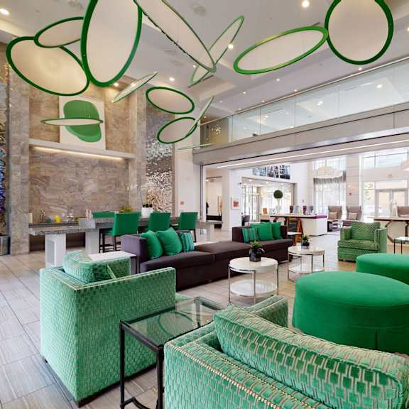 The lobby at Arpeggio with plush chairs, couches, an office desk, a coffee station, coffee tables, and foot stools. 