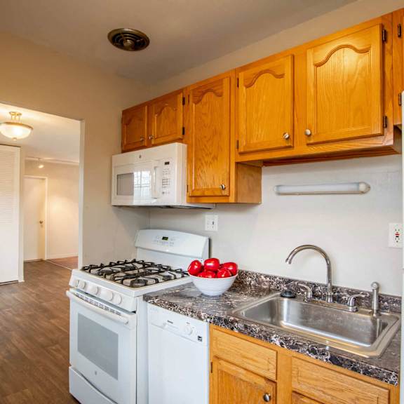 A kitchen with a stove, sink, and cabinets. at Michigan Street Apartment Homes, Michigan