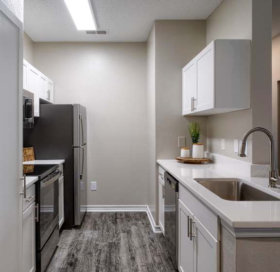 A kitchen with a black fridge and white cabinets.