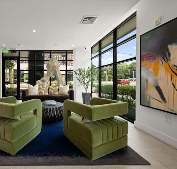 A living room with green chairs and a large painting on the wall.