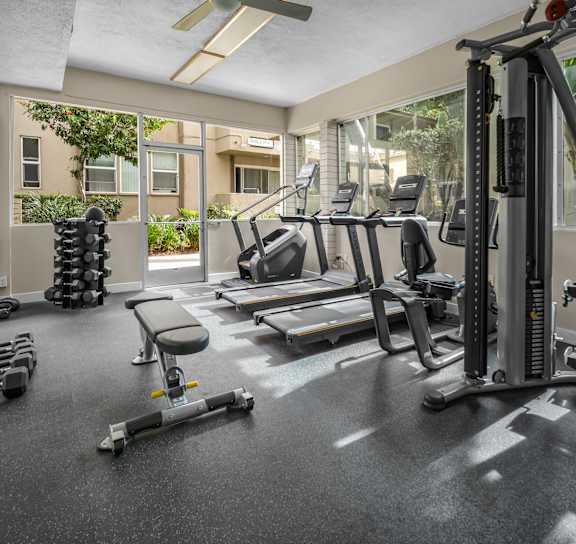 a gym with treadmills and other exercise equipment and a window at West Park Village, Los Angeles, California