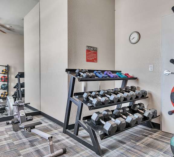 a gym with weights and dumbbells in the corner of a room at Aviara Apartments, San Jose 95116