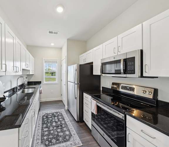 a kitchen with white cabinets and black counter tops