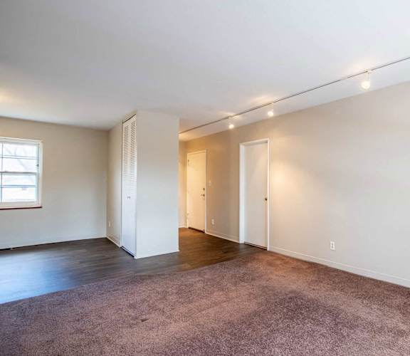 A large, empty room with a carpeted floor and white walls. at Michigan Street Apartment Homes, Michigan