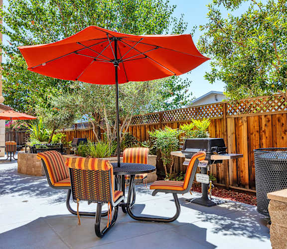 a patio with a red umbrella and chairs and tables